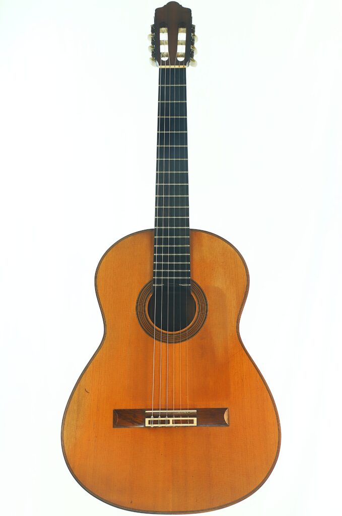 Eine Juan-Lopez-Aguilarte-Flamenco-Gitarre „Negra“ aus dem Jahr 1984 mit einem Holzkorpus, sechs Saiten und einem dunklen Griffbrett, fotografiert vor weißem Hintergrund. Eine Juan-Lopez-Aguilarte-Flamenco-Gitarre „Negra“ aus dem Jahr 1984 mit einem Holzkorpus, sechs Saiten und einem dunklen Griffbrett, fotografiert vor weißem Hintergrund.