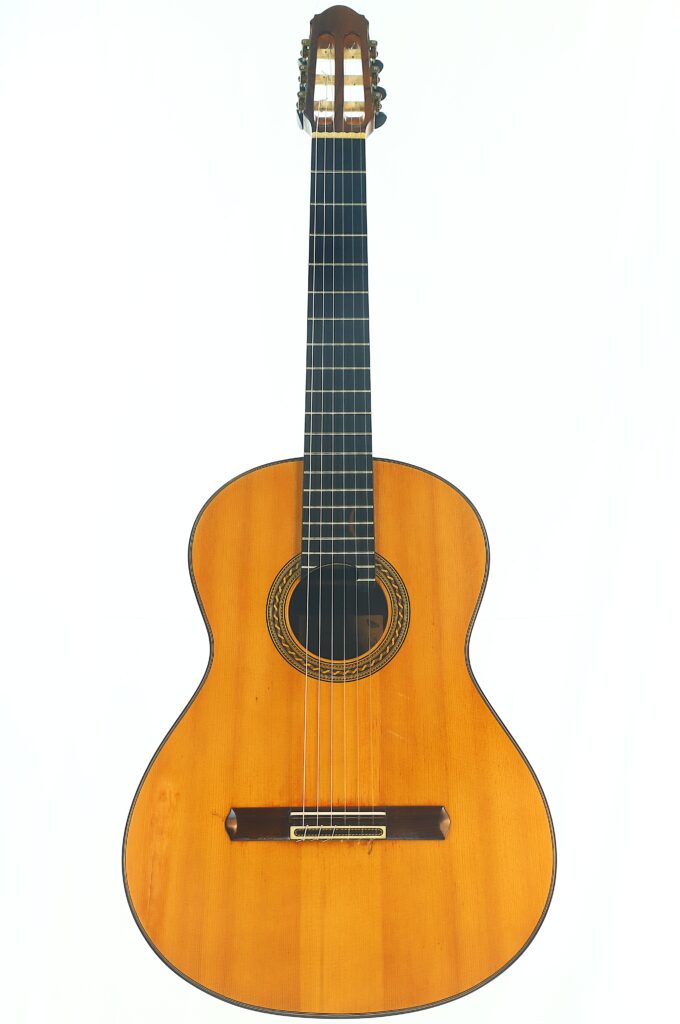 Eine Antonius Müller 2004 Doubletop Klassische Gitarre mit hellbraunem Holzkorpus, dunklem Griffbrett und sechs Nylonsaiten, aufrecht vor weißem Hintergrund fotografiert. Eine Antonius Müller 2004 Doubletop Klassische Gitarre mit hellbraunem Holzkorpus, dunklem Griffbrett und sechs Nylonsaiten, aufrecht vor weißem Hintergrund fotografiert.