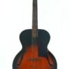 Eine Gibson L-48 Akustik Gitarre aus dem Jahr 1948 im Sunburst-Archtop-Design mit F-Löchern, einem dunklen Außenrand, der in einen helleren braunen Mittelbereich übergeht, und einem schwarzen Schlagbrett, abgebildet vor weißem Hintergrund. Eine Gibson L-48 Akustik Gitarre aus dem Jahr 1948 im Sunburst-Archtop-Design mit F-Löchern, einem dunklen Außenrand, der in einen helleren braunen Mittelbereich übergeht, und einem schwarzen Schlagbrett, abgebildet vor weißem Hintergrund.