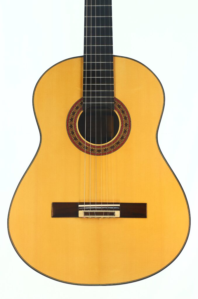 Die „Gerhard Arns 2026 Smallman Klassische Gitarre“ ist eine klassische Akustikgitarre mit einem Korpus aus hellem Holz, einer aufwendig gearbeiteten Rosette, die das Schallloch umgibt, und sechs Saiten, die vor einem weißen Hintergrund zu sehen sind. Die „Gerhard Arns 2026 Smallman Klassische Gitarre“ ist eine klassische Akustikgitarre mit einem Korpus aus hellem Holz, einer aufwendig gearbeiteten Rosette, die das Schallloch umgibt, und sechs Saiten, die vor einem weißen Hintergrund zu sehen sind.