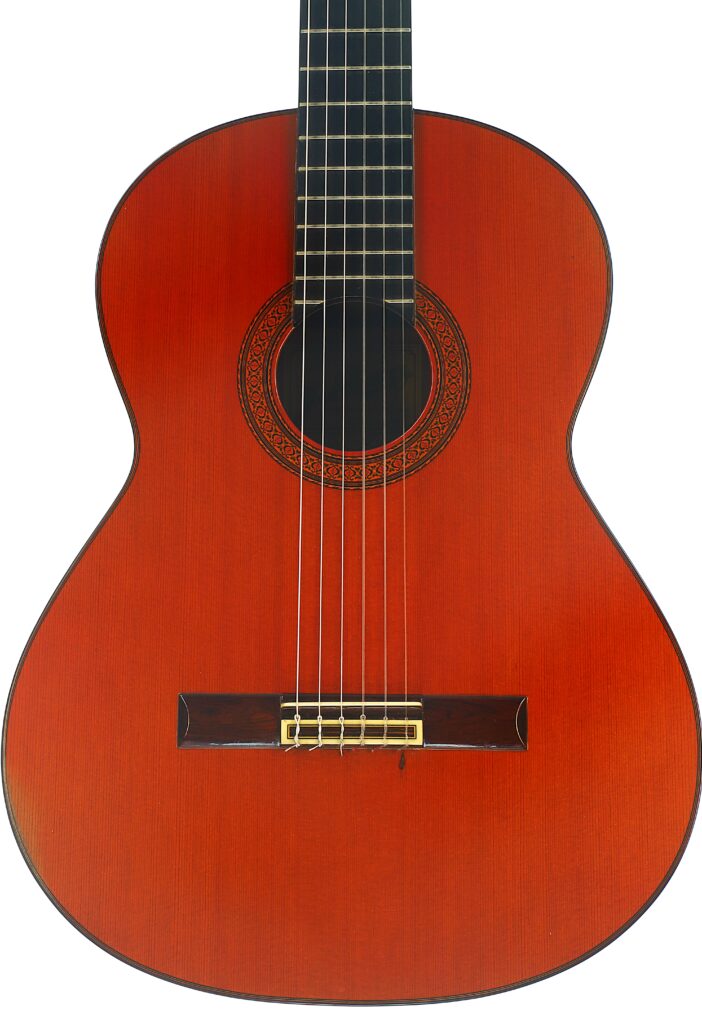 Eine Nahaufnahme einer Jose Ramirez 1a 1977 Klassische Gitarre mit einem rotbraunen Holzkorpus, Nylonsaiten und einer aufwendig verzierten Rosette um das Schallloch. Eine Nahaufnahme einer Jose Ramirez 1a 1977 Klassische Gitarre mit einem rotbraunen Holzkorpus, Nylonsaiten und einer aufwendig verzierten Rosette um das Schallloch.