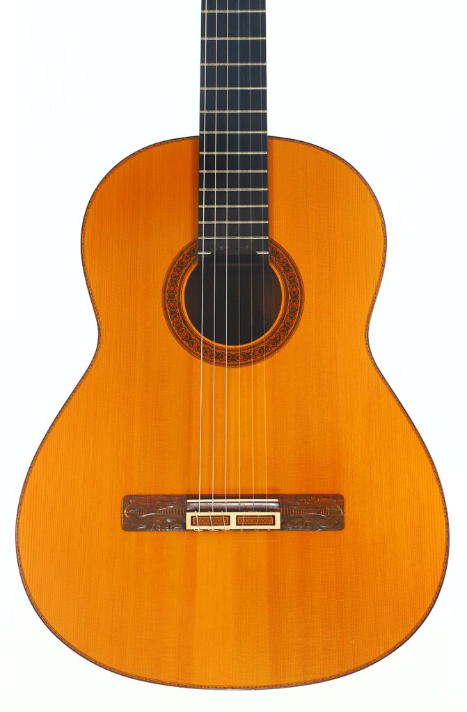 Die Flamenco-Gitarre „Jeronimo Pena 1976“ mit Holzkorpus, sechs Saiten und einer verzierten Rosette um das Schallloch ist vor einem weißen Hintergrund fotografiert. Die Flamenco-Gitarre „Jeronimo Pena 1976“ mit Holzkorpus, sechs Saiten und einer verzierten Rosette um das Schallloch ist vor einem weißen Hintergrund fotografiert.