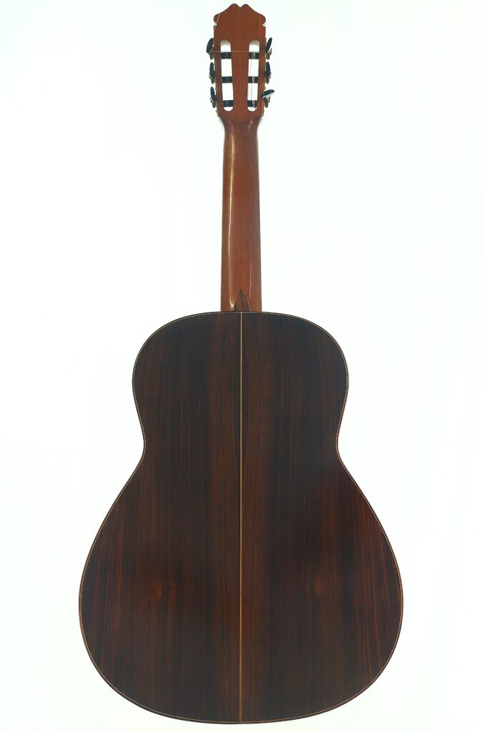Hier ist ein umformulierter Satz unter Verwendung der angegebenen Produktdaten: Die „Manuel Adalid Sr. 1971 Francisco Klassische Gitarre“ ist von hinten abgebildet und zeichnet sich durch eine polierte, dunkle Holzoberfläche mit einer sichtbaren Mittelnaht sowie einen hellbraunen Hals aus. Hier ist ein umformulierter Satz unter Verwendung der angegebenen Produktdaten: Die „Manuel Adalid Sr. 1971 Francisco Klassische Gitarre“ ist von hinten abgebildet und zeichnet sich durch eine polierte, dunkle Holzoberfläche mit einer sichtbaren Mittelnaht sowie einen hellbraunen Hals aus.