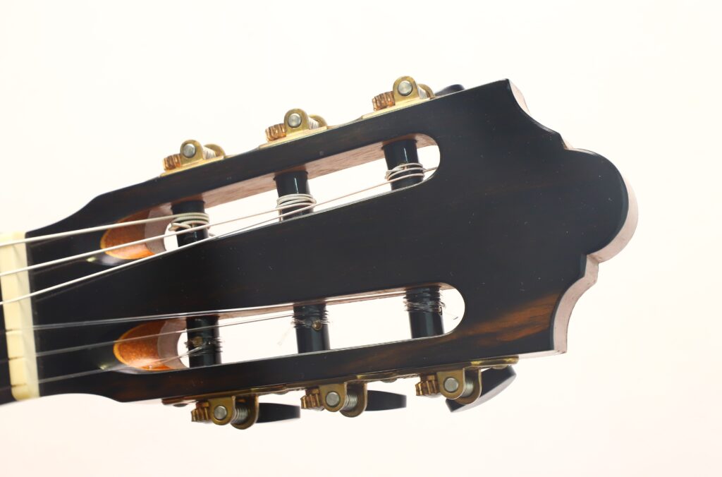 Nahaufnahme des Kopfes der „Friederich Klassische Gitarre“ von Stefan Nitschke aus dem Jahr 2015, bei der die Stimmwirbel, die Saiten und die dunkle Holzoberfläche vor einem schlichten, hellen Hintergrund besonders gut zur Geltung kommen. Nahaufnahme des Kopfes der „Friederich Klassische Gitarre“ von Stefan Nitschke aus dem Jahr 2015, bei der die Stimmwirbel, die Saiten und die dunkle Holzoberfläche vor einem schlichten, hellen Hintergrund besonders gut zur Geltung kommen.