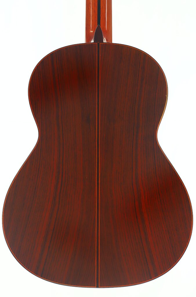 Rückansicht einer Jose Ramirez 1a 1977 Klassische Gitarre mit einem Korpus aus dunklem, poliertem Holz mit markanter Maserung und einer schmalen, hellen Mittelnaht. Rückansicht einer Jose Ramirez 1a 1977 Klassische Gitarre mit einem Korpus aus dunklem, poliertem Holz mit markanter Maserung und einer schmalen, hellen Mittelnaht.