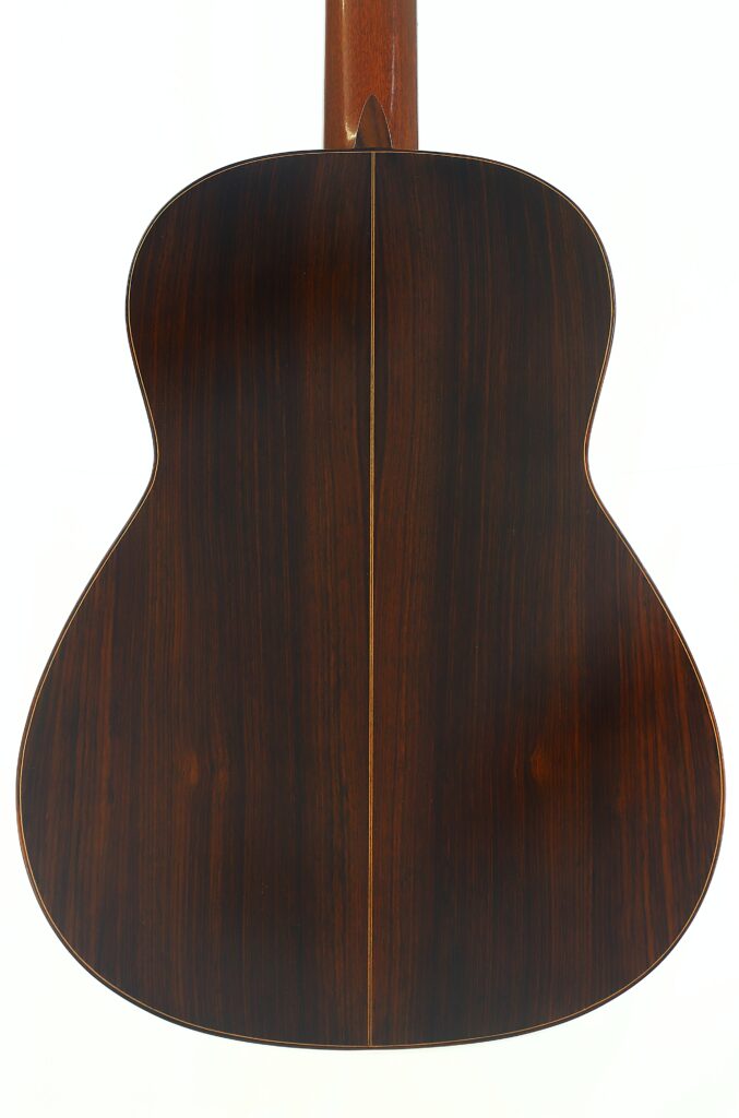 Die Rückseite der „Manuel Adalid Sr. 1971 Francisco Klassische Gitarre“ aus dunkelbraunem Holz mit gerader Mittelnaht und dezenten Holzmaserungen, fotografiert vor weißem Hintergrund. Die Rückseite der „Manuel Adalid Sr. 1971 Francisco Klassische Gitarre“ aus dunkelbraunem Holz mit gerader Mittelnaht und dezenten Holzmaserungen, fotografiert vor weißem Hintergrund.