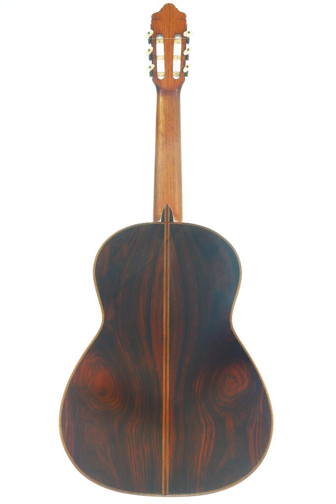 Die Rückansicht der Juan Lopez Aguilarte 1984 Negra Flamenco-Gitarre zeigt ihre dunklen Holzmaserungen, eine mittige Naht und einen Holzhals. Die Rückansicht der Juan Lopez Aguilarte 1984 Negra Flamenco-Gitarre zeigt ihre dunklen Holzmaserungen, eine mittige Naht und einen Holzhals.