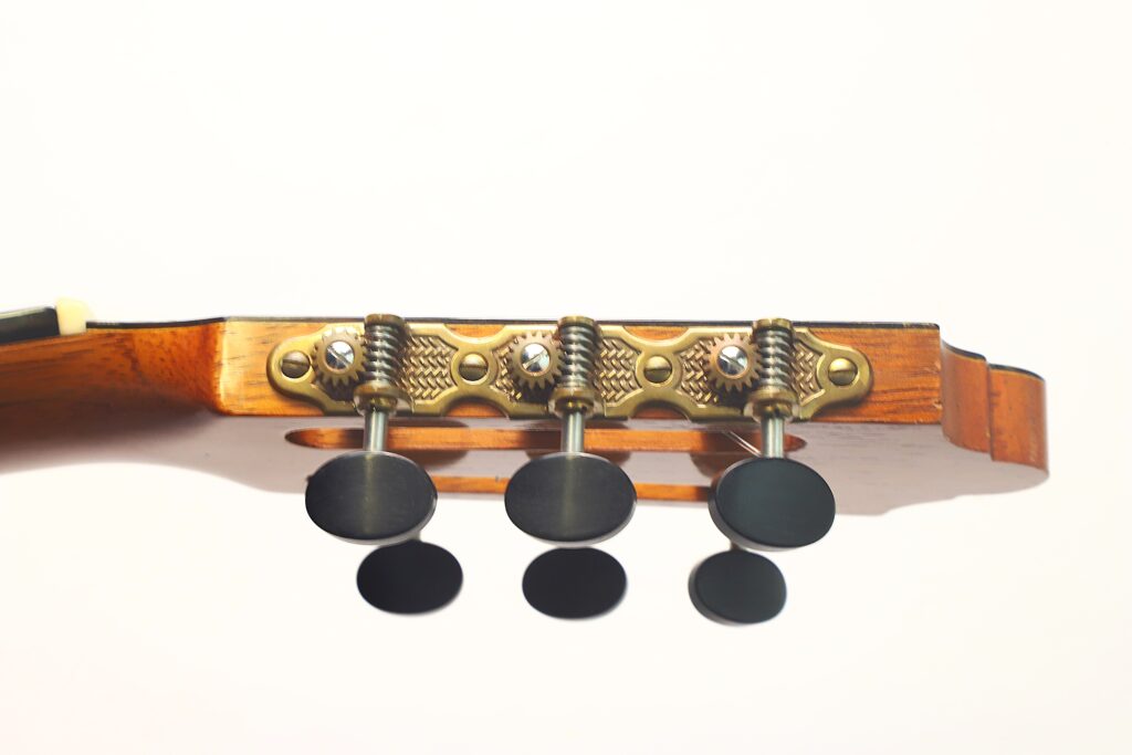 Nahaufnahme des Kopfes der „Friederich Klassische Gitarre“ von Stefan Nitschke aus dem Jahr 2015 mit drei schwarzen Stimmwirbeln und Metall-Stimmmechaniken vor weißem Hintergrund. Nahaufnahme des Kopfes der „Friederich Klassische Gitarre“ von Stefan Nitschke aus dem Jahr 2015 mit drei schwarzen Stimmwirbeln und Metall-Stimmmechaniken vor weißem Hintergrund.