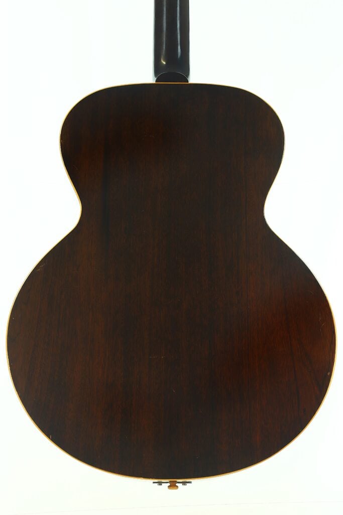 Die Rückseite der Gibson L-48 Akustikgitarre aus dem Jahr 1948 mit dunkler Holzoberfläche und sichtbarer Maserung, fotografiert vor weißem Hintergrund. Die Rückseite der Gibson L-48 Akustikgitarre aus dem Jahr 1948 mit dunkler Holzoberfläche und sichtbarer Maserung, fotografiert vor weißem Hintergrund.