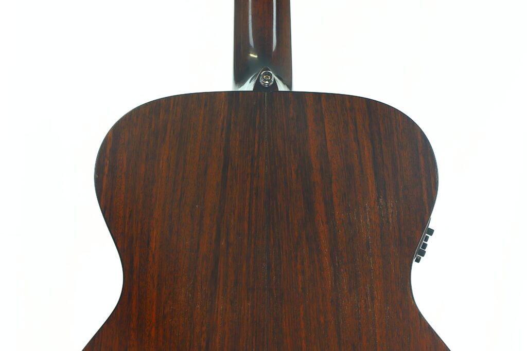 Nahaufnahme der Rückseite einer MARTIN OM-21 Akustikgitarre aus dem Jahr 1995, die ihre satte, dunkle Holzmaserung vor einem schlichten weißen Hintergrund zur Geltung bringt. Nahaufnahme der Rückseite einer MARTIN OM-21 Akustikgitarre aus dem Jahr 1995, die ihre satte, dunkle Holzmaserung vor einem schlichten weißen Hintergrund zur Geltung bringt.
