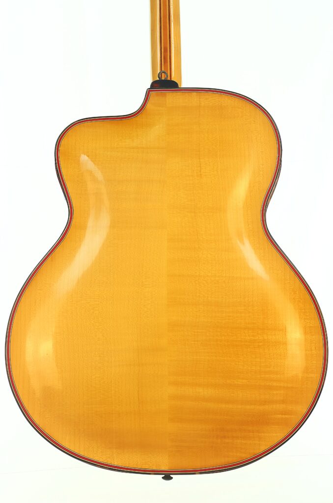 Die Rückseite einer Artur-Lang-Jazzgitarre aus den 1950er Jahren mit heller Holzoptik, geschwungener Form und glänzender Oberfläche, aufgenommen vor einem schlichten weißen Hintergrund. Die Rückseite einer Artur-Lang-Jazzgitarre aus den 1950er Jahren mit heller Holzoptik, geschwungener Form und glänzender Oberfläche, aufgenommen vor einem schlichten weißen Hintergrund.