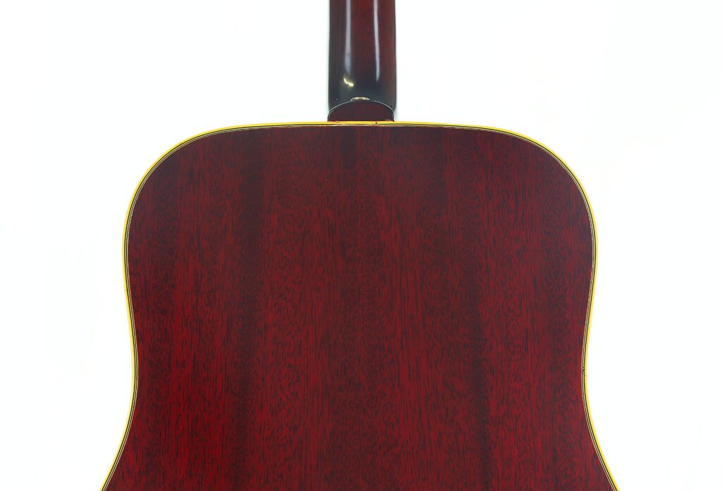 Die Rückseite der Gibson SJN 1968 Akustikgitarre mit einer polierten, dunkelrot-braunen Holzoberfläche und dezenten gelben Zierleisten, fotografiert vor weißem Hintergrund. Die Rückseite der Gibson SJN 1968 Akustikgitarre mit einer polierten, dunkelrot-braunen Holzoberfläche und dezenten gelben Zierleisten, fotografiert vor weißem Hintergrund.
