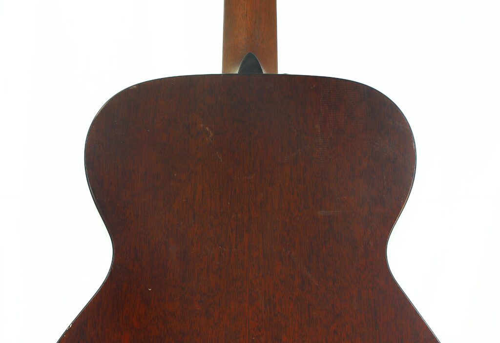 Das Bild zeigt die Rückseite einer Martin 000-18 Akustikgitarre aus dem Jahr 1960, die aus dunklem Holz gefertigt ist, eine glatte Oberfläche und dezente Holzmaserungen aufweist; oben ist der Hals zu sehen. Das Bild zeigt die Rückseite einer Martin 000-18 Akustikgitarre aus dem Jahr 1960, die aus dunklem Holz gefertigt ist, eine glatte Oberfläche und dezente Holzmaserungen aufweist; oben ist der Hals zu sehen.