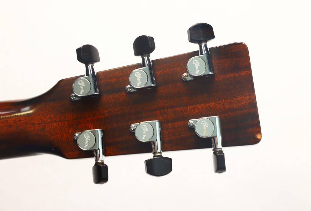 Die Rückseite des Kopfes der MARTIN OM-21 Akustikgitarre aus dem Jahr 1995 mit sechs Metallstimmwirbeln auf braunem Holz, aufgenommen vor einem schlichten weißen Hintergrund. Die Rückseite des Kopfes der MARTIN OM-21 Akustikgitarre aus dem Jahr 1995 mit sechs Metallstimmwirbeln auf braunem Holz, aufgenommen vor einem schlichten weißen Hintergrund.