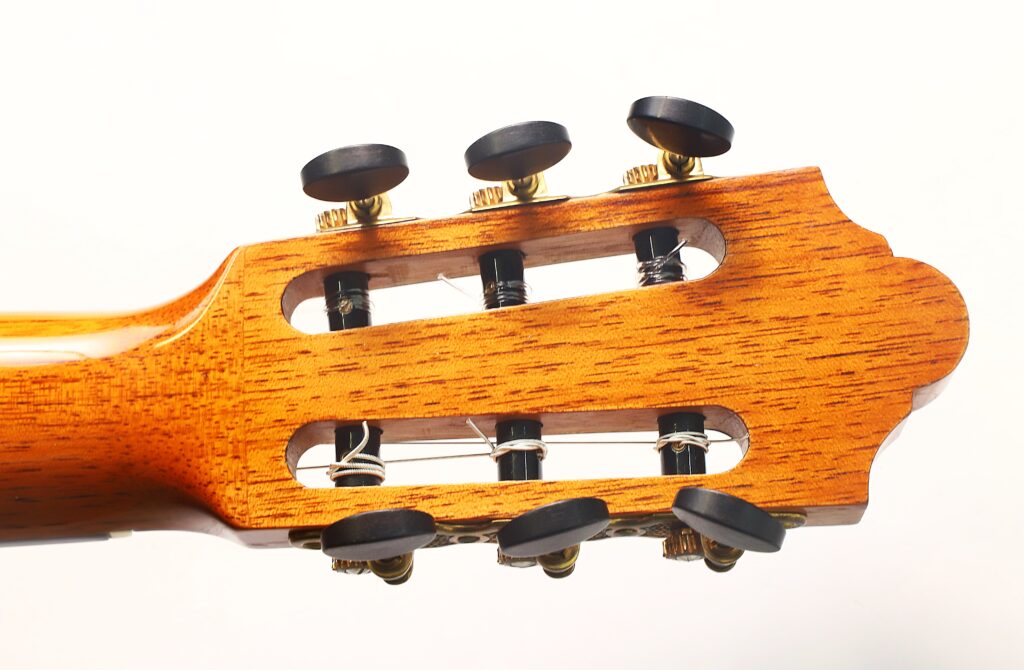 Nahaufnahme des Kopfes der „Friederich Klassische Gitarre“ von Stefan Nitschke aus dem Jahr 2015 mit sechs schwarzen Stimmwirbeln und sichtbaren Saitenwicklungen vor weißem Hintergrund. Nahaufnahme des Kopfes der „Friederich Klassische Gitarre“ von Stefan Nitschke aus dem Jahr 2015 mit sechs schwarzen Stimmwirbeln und sichtbaren Saitenwicklungen vor weißem Hintergrund.
