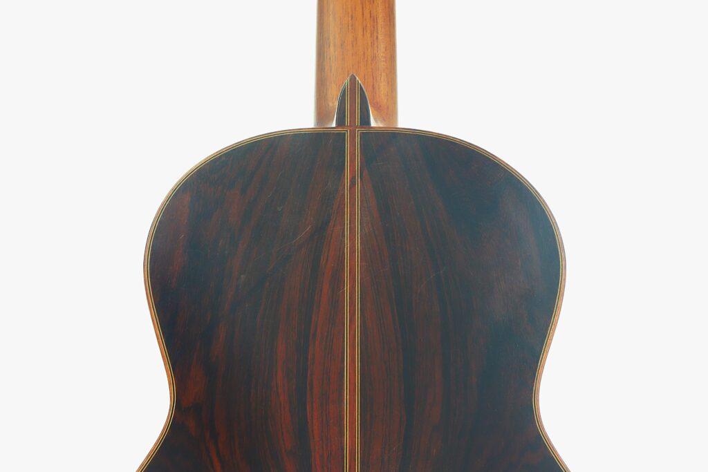 Die Rückseite der Juan Lopez Aguilarte 1984 Negra Flamenco-Gitarre weist eine dunkle, polierte Holzoberfläche mit einer kontrastierenden Einlage in der Mitte auf, die vor einem schlichten weißen Hintergrund zu sehen ist. Die Rückseite der Juan Lopez Aguilarte 1984 Negra Flamenco-Gitarre weist eine dunkle, polierte Holzoberfläche mit einer kontrastierenden Einlage in der Mitte auf, die vor einem schlichten weißen Hintergrund zu sehen ist.
