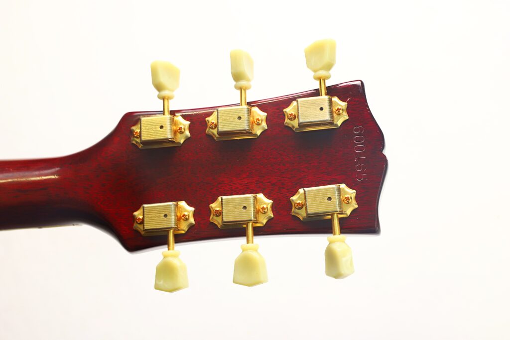 Nahaufnahme der Rückseite des Kopfes einer Gibson SJN 1968 Akustikgitarre, auf der sechs goldene Stimmwirbel mit cremefarbenen Stimmknöpfen vor weißem Hintergrund zu sehen sind. Nahaufnahme der Rückseite des Kopfes einer Gibson SJN 1968 Akustikgitarre, auf der sechs goldene Stimmwirbel mit cremefarbenen Stimmknöpfen vor weißem Hintergrund zu sehen sind.