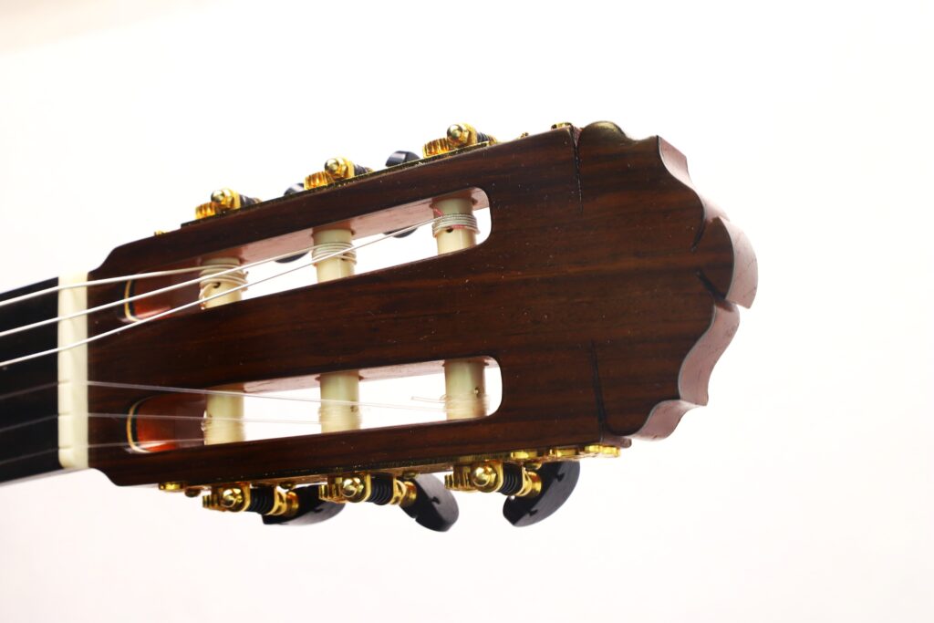 Nahaufnahme des Kopfes einer Gerhard Arns 2026 Smallman Klassische Gitarre mit goldenen Stimmwirbeln und weißen Stimmstiften vor einem schlichten weißen Hintergrund. Nahaufnahme des Kopfes einer Gerhard Arns 2026 Smallman Klassische Gitarre mit goldenen Stimmwirbeln und weißen Stimmstiften vor einem schlichten weißen Hintergrund.