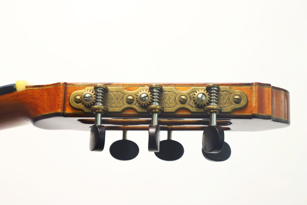 Nahaufnahme der Stimmwirbel und Zahnräder am Kopf einer Antonius Müller „Doubletop Klassische Gitarre“ aus dem Jahr 2004 vor einem schlichten weißen Hintergrund. Nahaufnahme der Stimmwirbel und Zahnräder am Kopf einer Antonius Müller „Doubletop Klassische Gitarre“ aus dem Jahr 2004 vor einem schlichten weißen Hintergrund.