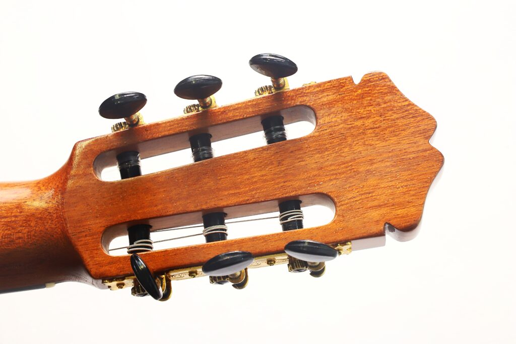 Nahaufnahme des Kopfes der „Manuel Adalid Sr. 1971 Francisco Klassische Gitarre“ mit sechs Stimmwirbeln, goldfarbener Beschlag und sichtbarer Holzmaserung vor weißem Hintergrund. Nahaufnahme des Kopfes der „Manuel Adalid Sr. 1971 Francisco Klassische Gitarre“ mit sechs Stimmwirbeln, goldfarbener Beschlag und sichtbarer Holzmaserung vor weißem Hintergrund.