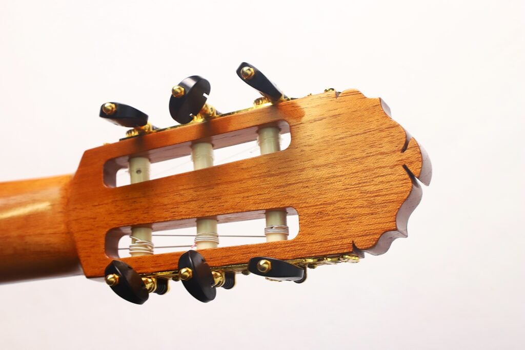Nahaufnahme des Kopfes der „Gerhard Arns 2026 Smallman Klassische Gitarre“ mit Stimmwirbeln und Nylonsaiten, die die Holzmaserung und die detailreiche Handwerkskunst vor einem schlichten weißen Hintergrund hervorhebt. Nahaufnahme des Kopfes der „Gerhard Arns 2026 Smallman Klassische Gitarre“ mit Stimmwirbeln und Nylonsaiten, die die Holzmaserung und die detailreiche Handwerkskunst vor einem schlichten weißen Hintergrund hervorhebt.
