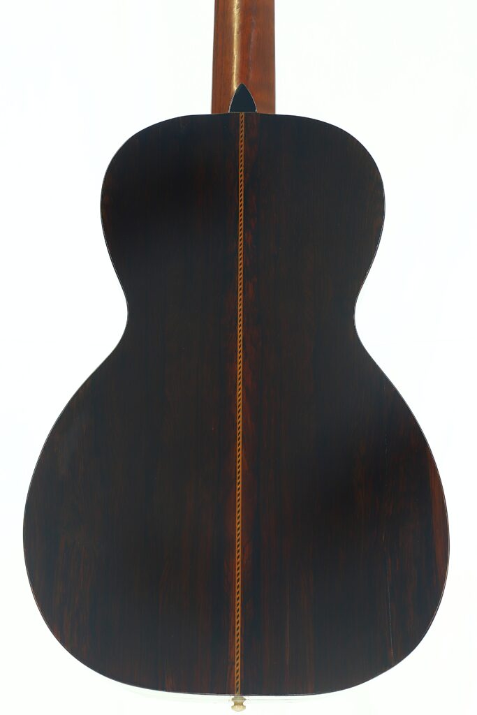 Die Rückseite der Washburn 1900 Parlor-Akustikgitarre mit dunklem Holz und einer Zierintarsie in der Mitte, fotografiert vor weißem Hintergrund. Die Rückseite der Washburn 1900 Parlor-Akustikgitarre mit dunklem Holz und einer Zierintarsie in der Mitte, fotografiert vor weißem Hintergrund.