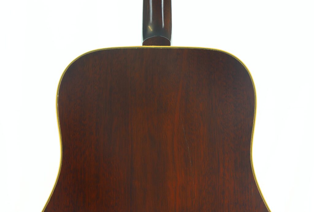 Die Rückseite der Gibson Hummingbird 1968 Akustikgitarre weist eine dunkle Holzoberfläche mit gelber Einfassung auf und wurde vor einem weißen Hintergrund fotografiert. Die Rückseite der Gibson Hummingbird 1968 Akustikgitarre weist eine dunkle Holzoberfläche mit gelber Einfassung auf und wurde vor einem weißen Hintergrund fotografiert.