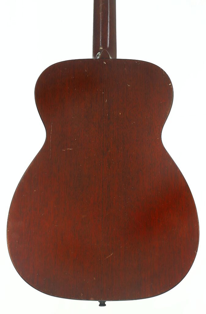 Rückansicht der Martin 00-18 Akustikgitarre aus dem Jahr 1953 mit einer dunkelbraunen Holzoberfläche, die die Maserung und die dezenten Gebrauchsspuren auf der Oberfläche hervorhebt. Rückansicht der Martin 00-18 Akustikgitarre aus dem Jahr 1953 mit einer dunkelbraunen Holzoberfläche, die die Maserung und die dezenten Gebrauchsspuren auf der Oberfläche hervorhebt.