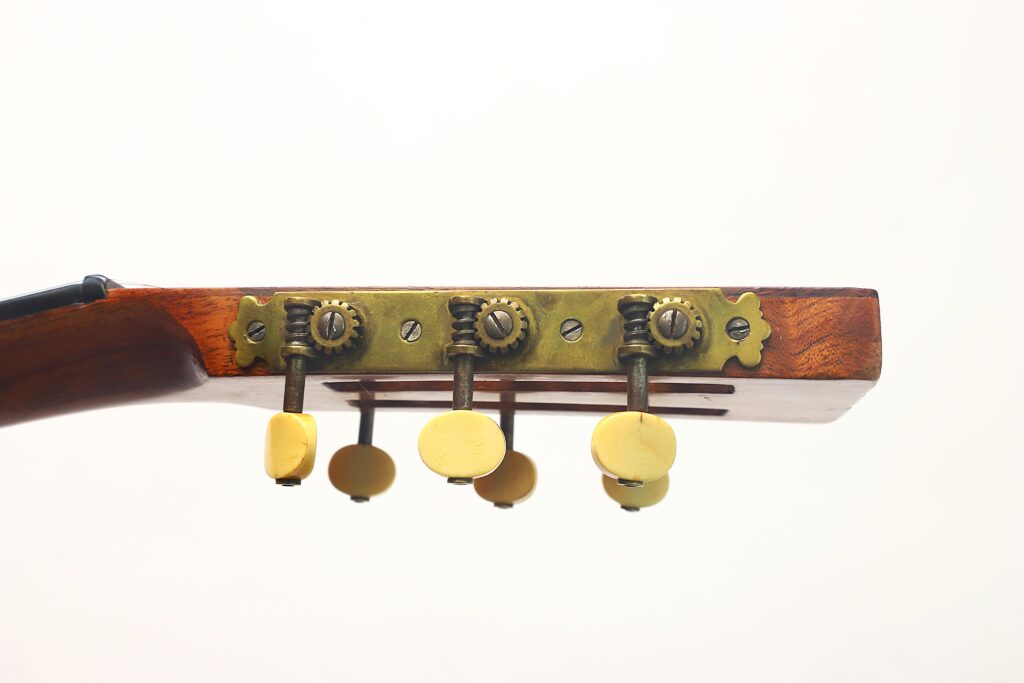 Nahaufnahme des Kopfes der Washburn 1900 Parlor-Akustikgitarre mit vier gelben Stimmwirbeln, die auf Messing-Stimmmechaniken montiert sind, vor einem schlichten weißen Hintergrund. Nahaufnahme des Kopfes der Washburn 1900 Parlor-Akustikgitarre mit vier gelben Stimmwirbeln, die auf Messing-Stimmmechaniken montiert sind, vor einem schlichten weißen Hintergrund.