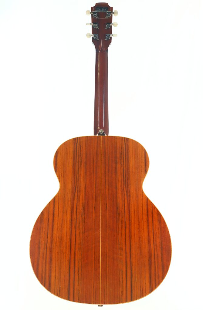 Das Bild zeigt die Rückansicht einer Lowden G-7-Akustikgitarre aus den 1980er Jahren mit einer Holzoberfläche, auf der die Maserung sichtbar ist, und einer glänzenden Oberfläche. Auch der Hals und die Stimmwirbel der Gitarre sind zu sehen. Das Bild zeigt die Rückansicht einer Lowden G-7-Akustikgitarre aus den 1980er Jahren mit einer Holzoberfläche, auf der die Maserung sichtbar ist, und einer glänzenden Oberfläche. Auch der Hals und die Stimmwirbel der Gitarre sind zu sehen.