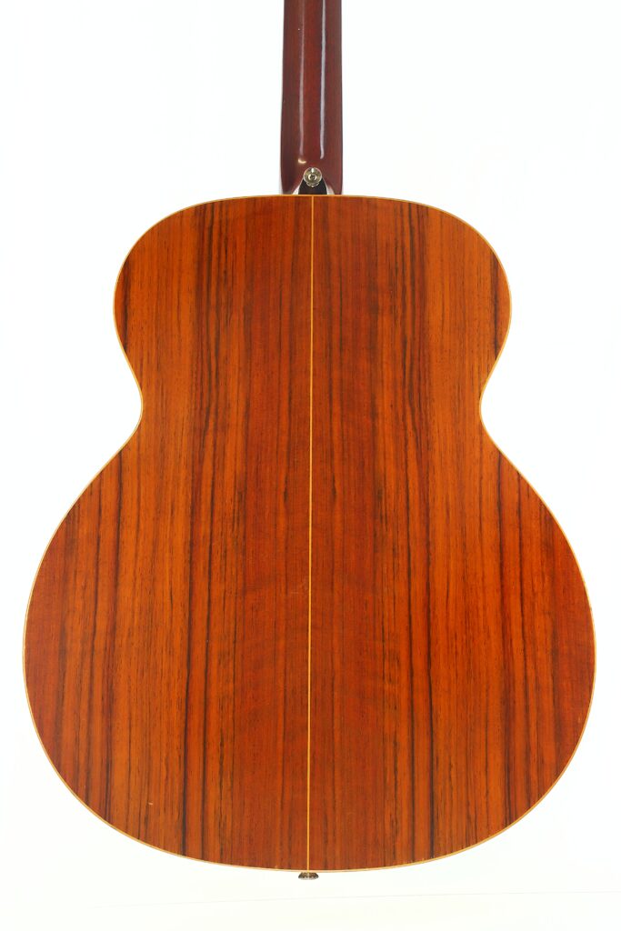 Das Bild zeigt die Rückseite einer Lowden G-7-Akustikgitarre aus den 1980er Jahren mit poliertem Holz, einer vertikalen Naht in der Mitte und sichtbaren natürlichen Holzmaserungen. Das Bild zeigt die Rückseite einer Lowden G-7-Akustikgitarre aus den 1980er Jahren mit poliertem Holz, einer vertikalen Naht in der Mitte und sichtbaren natürlichen Holzmaserungen.