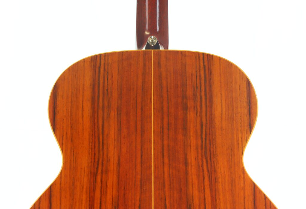 Die Rückseite der Lowden G-7 Akustikgitarre aus den 1980er Jahren weist eine polierte Holzoberfläche mit sichtbarer Maserung und einer vertikal verlaufenden Mittelnaht auf. Die Rückseite der Lowden G-7 Akustikgitarre aus den 1980er Jahren weist eine polierte Holzoberfläche mit sichtbarer Maserung und einer vertikal verlaufenden Mittelnaht auf.