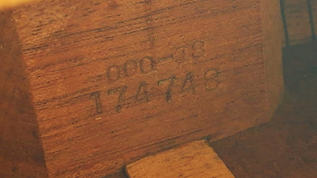 Eine Nahaufnahme der Holzoberfläche einer Martin 000-18 Akustikgitarre aus dem Jahr 1960 zeigt zwei handgeschriebene Zahlenfolgen – oben „000-48“ und unten „174748“ –, die direkt in die Holzmaserung eingraviert sind. Eine Nahaufnahme der Holzoberfläche einer Martin 000-18 Akustikgitarre aus dem Jahr 1960 zeigt zwei handgeschriebene Zahlenfolgen – oben „000-48“ und unten „174748“ –, die direkt in die Holzmaserung eingraviert sind.