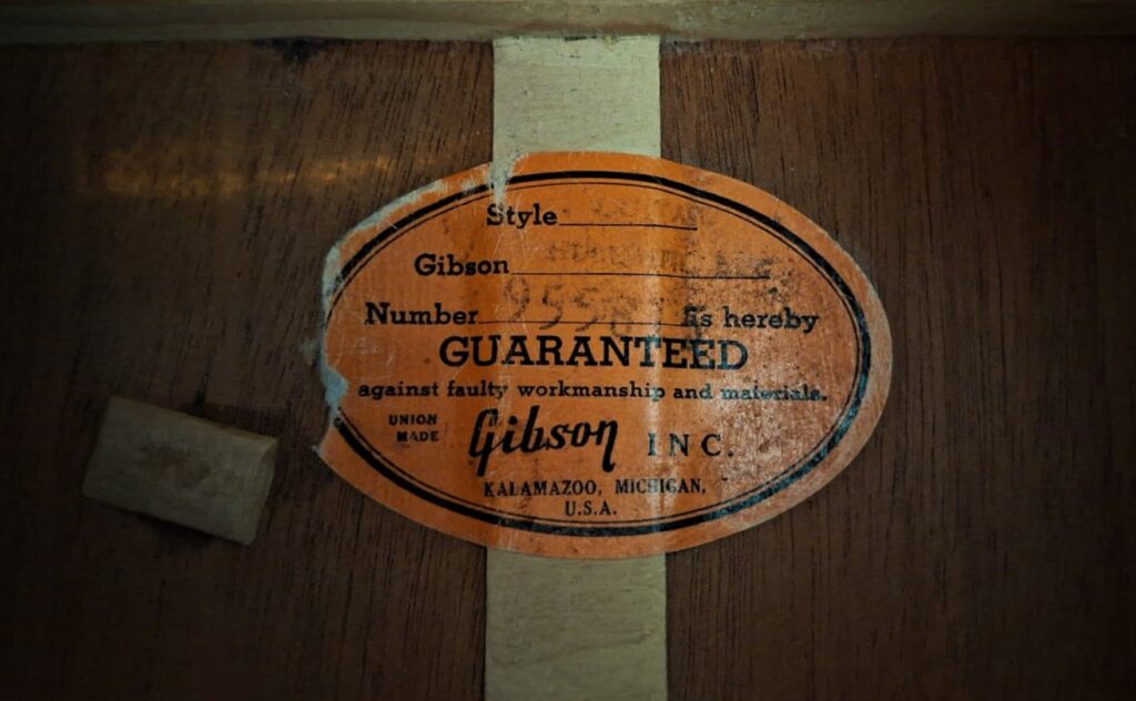 Im Inneren des Holzkörpers der Gibson Hummingbird 1968 Akustikgitarre befindet sich ein orangefarbenes Gibson Inc.-Etikett, auf dem die Seriennummer, der Herstellungsort (Kalamazoo, Michigan) sowie eine Garantie gegen Material- und Verarbeitungsfehler angegeben sind. Im Inneren des Holzkörpers der Gibson Hummingbird 1968 Akustikgitarre befindet sich ein orangefarbenes Gibson Inc.-Etikett, auf dem die Seriennummer, der Herstellungsort (Kalamazoo, Michigan) sowie eine Garantie gegen Material- und Verarbeitungsfehler angegeben sind.