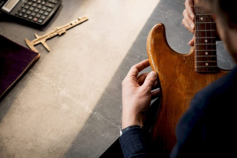 Dealer inspecting guitar for consignment valuation