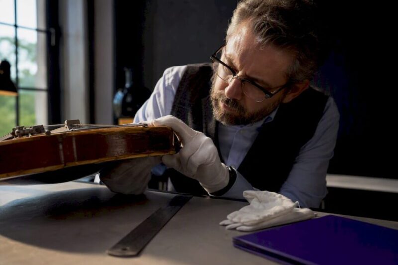 Specialist examining vintage guitar for insurance appraisal