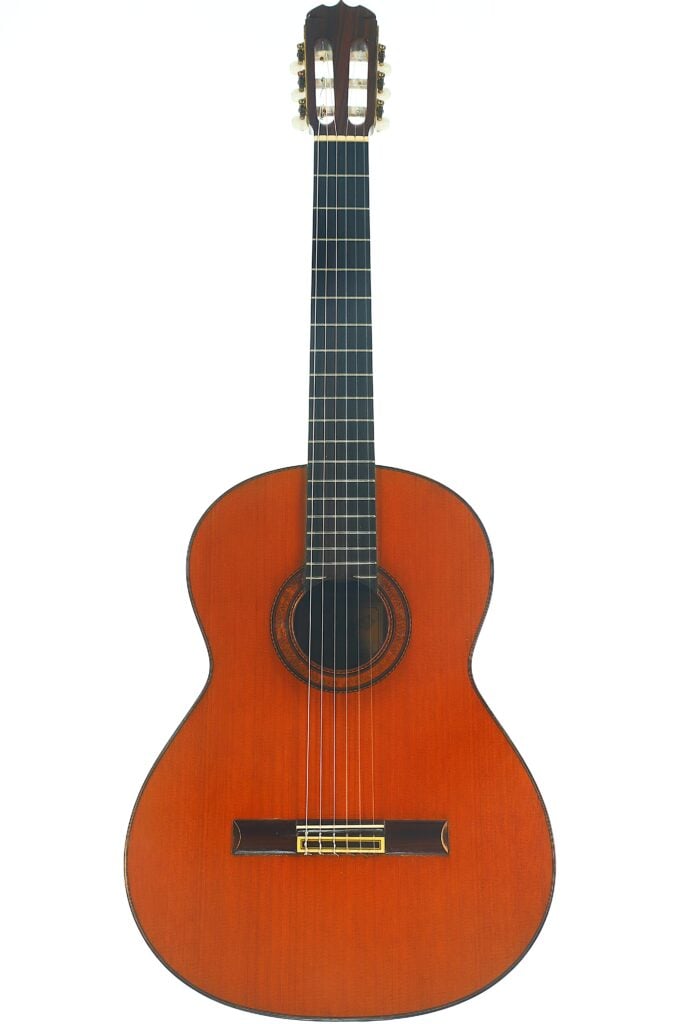 Eine klassische Gitarre vom Typ Ramirez 1a aus dem Jahr 1985 mit einem Holzkorpus, einem dunklen Griffbrett und sechs Saiten ist vor einem schlichten weißen Hintergrund fotografiert. Eine klassische Gitarre vom Typ Ramirez 1a aus dem Jahr 1985 mit einem Holzkorpus, einem dunklen Griffbrett und sechs Saiten ist vor einem schlichten weißen Hintergrund fotografiert.