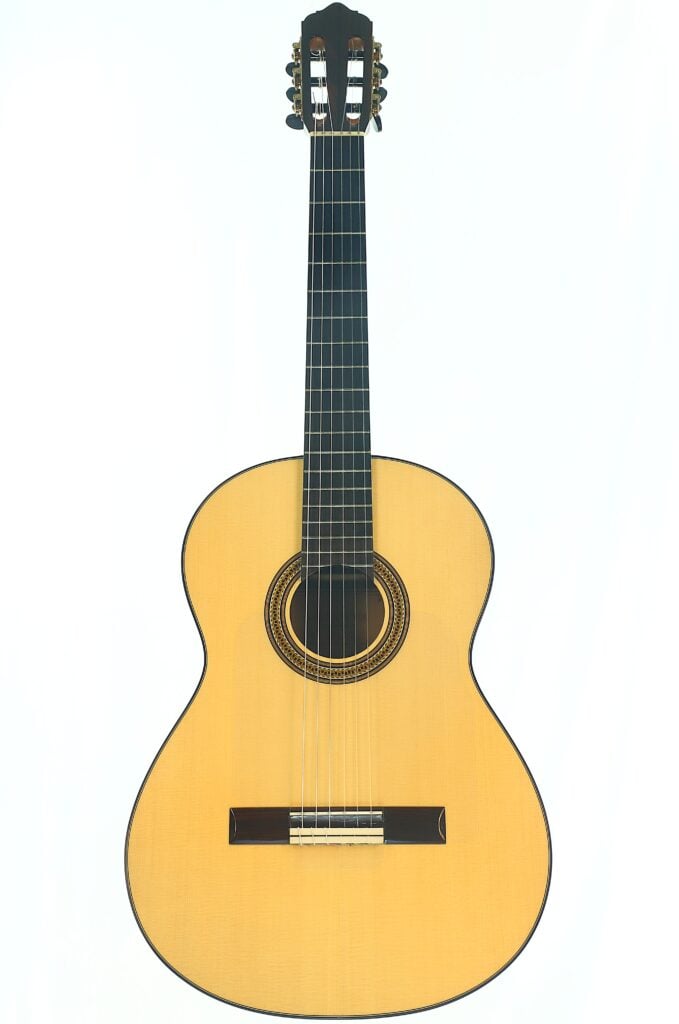 Eine Lester DeVoe 2020 Negra Flamenco Gitarre mit hellem Korpus, dunklem Griffbrett und sechs Saiten, fotografiert vor einem schlichten weißen Hintergrund. Eine Lester DeVoe 2020 Negra Flamenco Gitarre mit hellem Korpus, dunklem Griffbrett und sechs Saiten, fotografiert vor einem schlichten weißen Hintergrund.