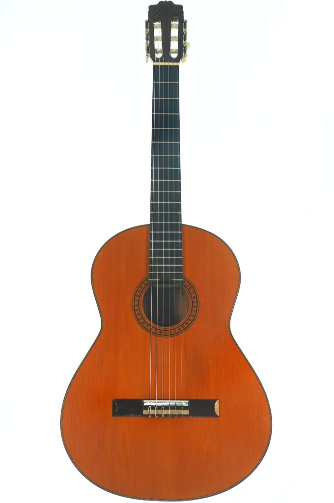 Eine Flamenco-Gitarre von Casa Arcangel Fernandez aus dem Jahr 1970 mit Holzkorpus, sechs Saiten und einem dunklen Griffbrett, fotografiert vor weißem Hintergrund. Eine Flamenco-Gitarre von Casa Arcangel Fernandez aus dem Jahr 1970 mit Holzkorpus, sechs Saiten und einem dunklen Griffbrett, fotografiert vor weißem Hintergrund.