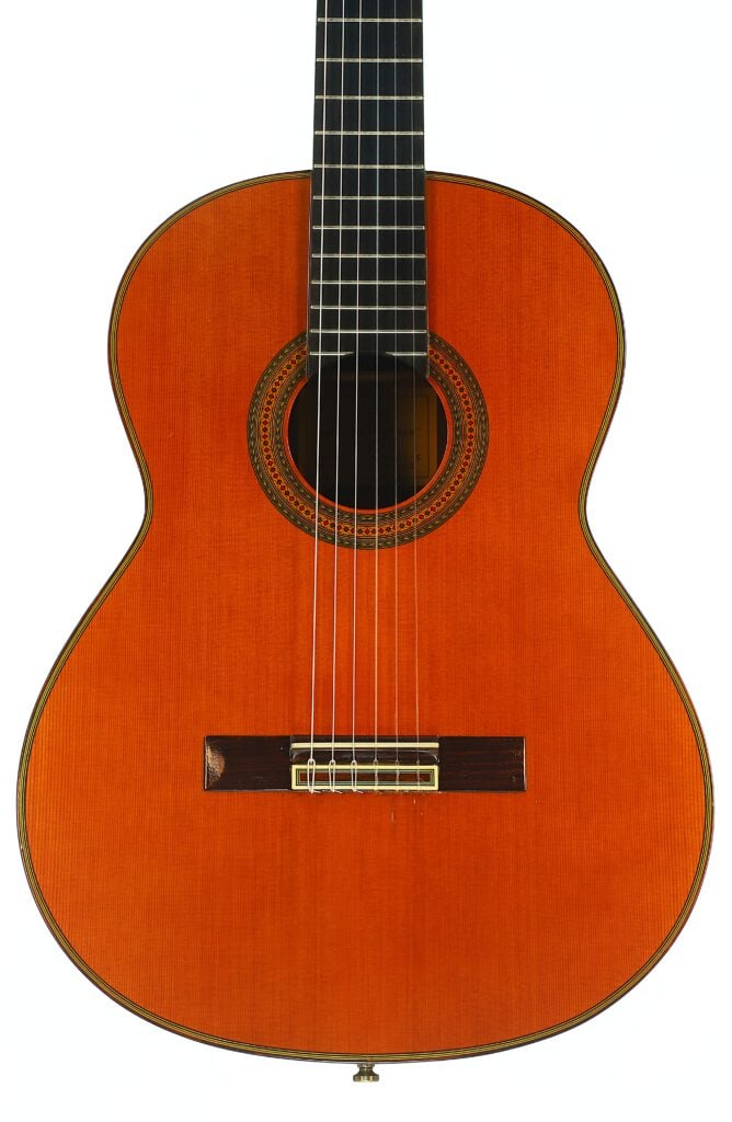 Vorderansicht der Paulino Bernabe M-5 2008 Klassische Gitarre, einer klassischen Akustikgitarre mit sechs Saiten, einem Holzkorpus, einer dekorativen Rosette um das Schallloch und einem dunklen Griffbrett. Vorderansicht der Paulino Bernabe M-5 2008 Klassische Gitarre, einer klassischen Akustikgitarre mit sechs Saiten, einem Holzkorpus, einer dekorativen Rosette um das Schallloch und einem dunklen Griffbrett.