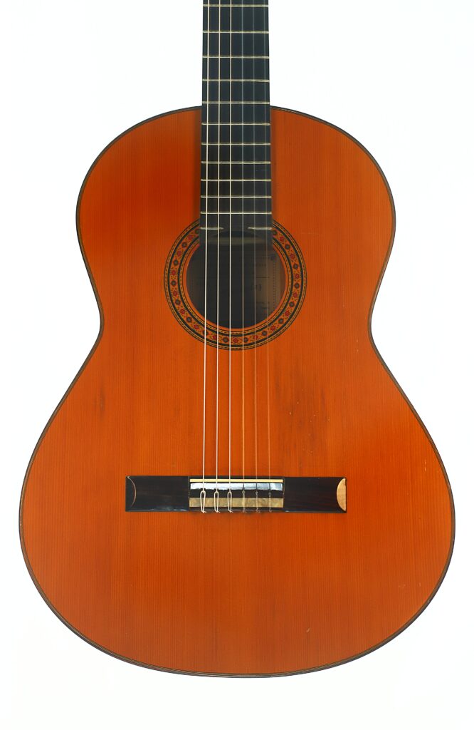 Eine Flamenco-Gitarre von Casa Arcangel Fernandez aus dem Jahr 1970 mit braunem Holzkorpus und sechs Saiten wird vor einem schlichten weißen Hintergrund präsentiert. Eine Flamenco-Gitarre von Casa Arcangel Fernandez aus dem Jahr 1970 mit braunem Holzkorpus und sechs Saiten wird vor einem schlichten weißen Hintergrund präsentiert.