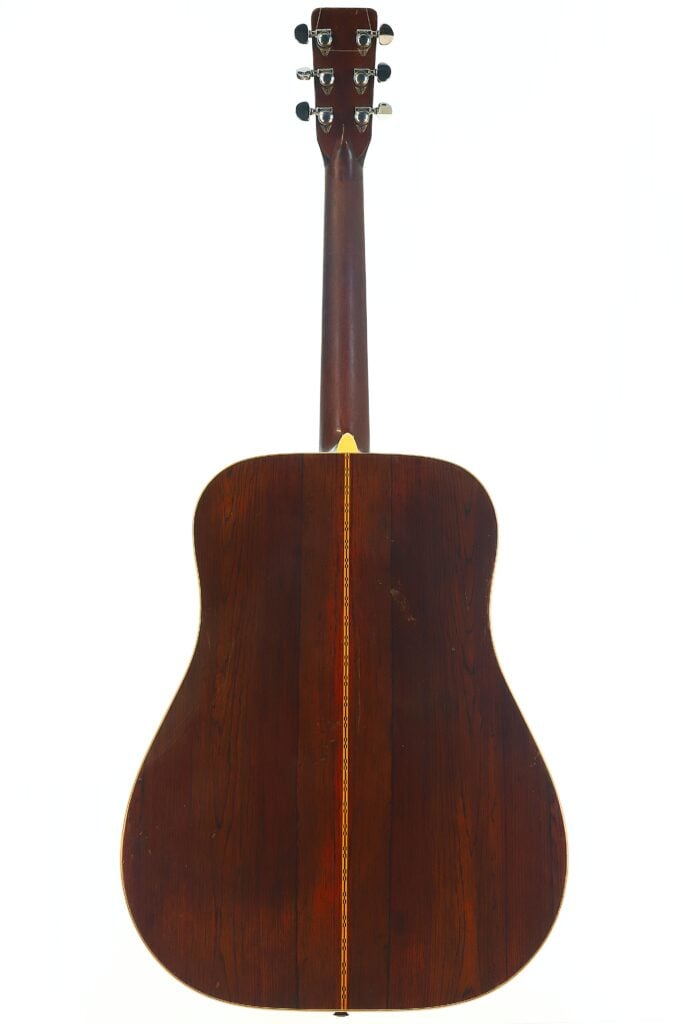 Die Rückansicht der Martin D-28 Akustikgitarre aus dem Jahr 1965 zeigt die dunkle Holzoberfläche, eine vertikale Zierintarsie, die in der Mitte entlangläuft, sowie die verchromten Stimmwirbel, die am Kopfstück zu sehen sind. Die Rückansicht der Martin D-28 Akustikgitarre aus dem Jahr 1965 zeigt die dunkle Holzoberfläche, eine vertikale Zierintarsie, die in der Mitte entlangläuft, sowie die verchromten Stimmwirbel, die am Kopfstück zu sehen sind.