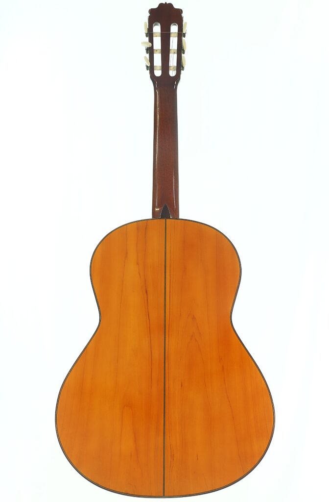 Die Rückansicht der Flamenco-Gitarre „Casa Arcangel Fernandez 1970“ besticht durch ihre Naturholz-Oberfläche mit einem dunklen, vertikalen Mittelstreifen, der den Hals, die Stimmwirbel und die charakteristischen Maserungen hervorhebt. Die Rückansicht der Flamenco-Gitarre „Casa Arcangel Fernandez 1970“ besticht durch ihre Naturholz-Oberfläche mit einem dunklen, vertikalen Mittelstreifen, der den Hals, die Stimmwirbel und die charakteristischen Maserungen hervorhebt.