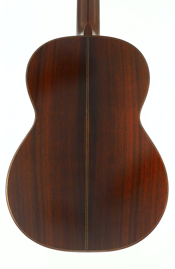 Vor einem weißen Hintergrund fotografiert, zeigt die Rückseite der „Tosca Klassische Gitarre“ von Frank-Peter Dietrich aus dem Jahr 1998 poliertes dunkles Holz mit einer mittigen Fuge und dezenten Maserungen. Vor einem weißen Hintergrund fotografiert, zeigt die Rückseite der „Tosca Klassische Gitarre“ von Frank-Peter Dietrich aus dem Jahr 1998 poliertes dunkles Holz mit einer mittigen Fuge und dezenten Maserungen.