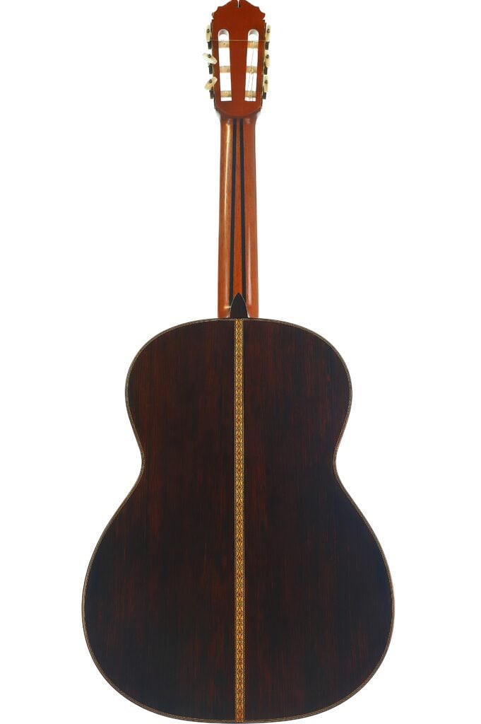 Die Rückansicht der „Masaru Kohno Modell 50 1979 Klassische Gitarre“ zeigt ihren dunklen Holzkorpus mit einem hellen Zierstreifen in der Mitte und einen braunen Hals mit weißen Stimmwirbeln. Die Rückansicht der „Masaru Kohno Modell 50 1979 Klassische Gitarre“ zeigt ihren dunklen Holzkorpus mit einem hellen Zierstreifen in der Mitte und einen braunen Hals mit weißen Stimmwirbeln.