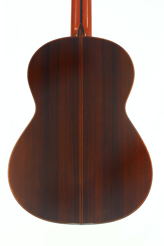 Die Rückseite der Ramirez 1a 1985 Klassische Gitarre weist eine glänzende, dunkle Holzoberfläche auf, durch deren Mitte eine vertikale Naht verläuft. Die Rückseite der Ramirez 1a 1985 Klassische Gitarre weist eine glänzende, dunkle Holzoberfläche auf, durch deren Mitte eine vertikale Naht verläuft.