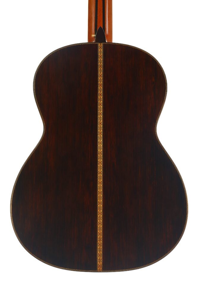 Rückansicht der „Masaru Kohno Modell 50 1979“ Klassische Gitarre mit dunkler Holzmaserung und einem dekorativen Einlegestreifen, der vertikal in der Mitte verläuft. Rückansicht der „Masaru Kohno Modell 50 1979“ Klassische Gitarre mit dunkler Holzmaserung und einem dekorativen Einlegestreifen, der vertikal in der Mitte verläuft.
