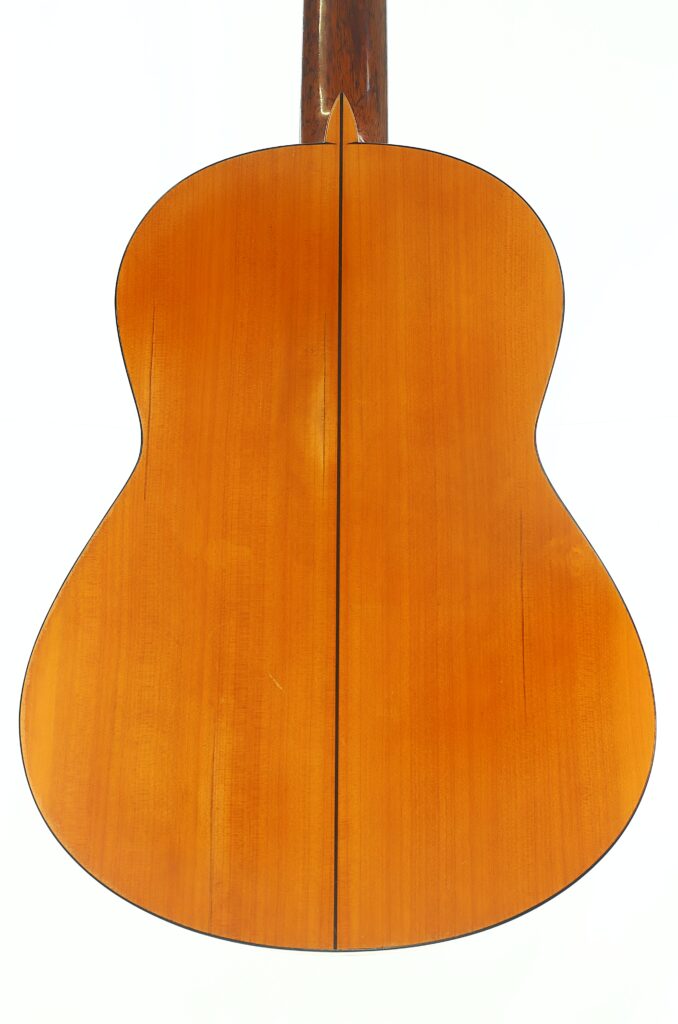 Das Bild zeigt die Rückseite einer Flamenco-Gitarre von Francisco Barba aus dem Jahr 1966 mit einer warmen braunen Lackierung und einer dunklen Linie, die vertikal in der Mitte verläuft. Das Bild zeigt die Rückseite einer Flamenco-Gitarre von Francisco Barba aus dem Jahr 1966 mit einer warmen braunen Lackierung und einer dunklen Linie, die vertikal in der Mitte verläuft.