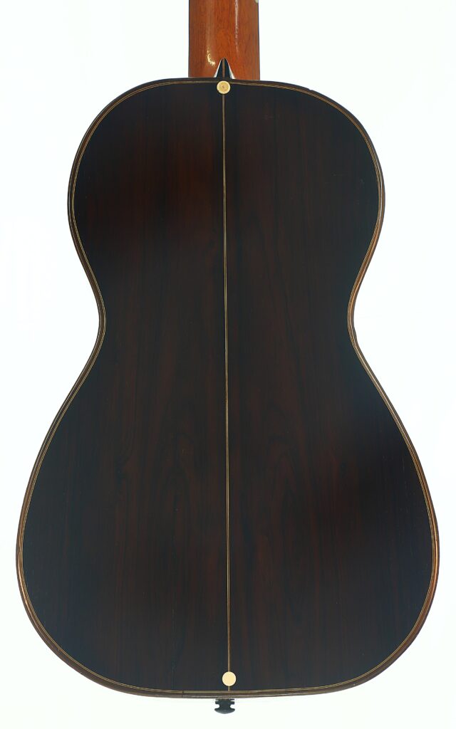 Die Rückseite einer „Romantikgitarre“ von Louis Panormo aus dem Jahr 1827, gekennzeichnet durch dunkles Holz, helle Einfassungen und eine vertikale Einlage, die in der Mitte verläuft, fotografiert vor weißem Hintergrund. Die Rückseite einer „Romantikgitarre“ von Louis Panormo aus dem Jahr 1827, gekennzeichnet durch dunkles Holz, helle Einfassungen und eine vertikale Einlage, die in der Mitte verläuft, fotografiert vor weißem Hintergrund.