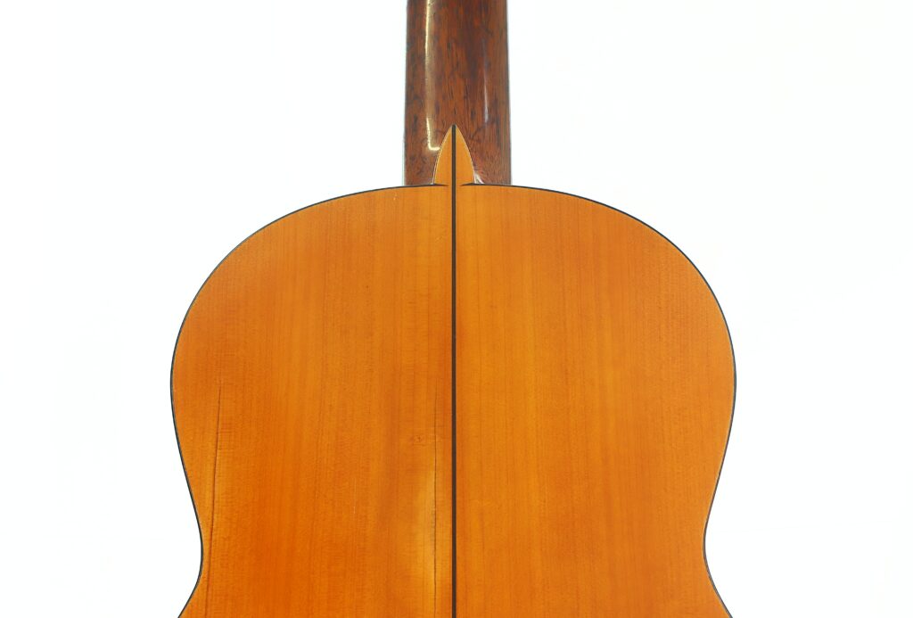 Nahaufnahme der Rückseite einer Flamenco-Gitarre von Francisco Barba aus dem Jahr 1966, die den Holzkorpus mit einer vertikalen Naht in der Mitte sowie einen Teil des Halses zeigt, alles vor weißem Hintergrund. Nahaufnahme der Rückseite einer Flamenco-Gitarre von Francisco Barba aus dem Jahr 1966, die den Holzkorpus mit einer vertikalen Naht in der Mitte sowie einen Teil des Halses zeigt, alles vor weißem Hintergrund.